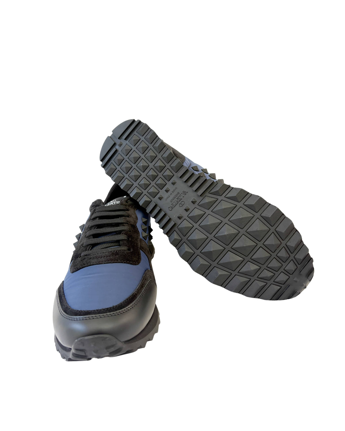 Angled profile view of Valentino Rockrunner trainer showcasing black rubber outsole and navy suede upper.